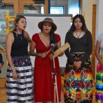 Kind Hart Women Singers standing around a microphone while they’re singing and drumming.