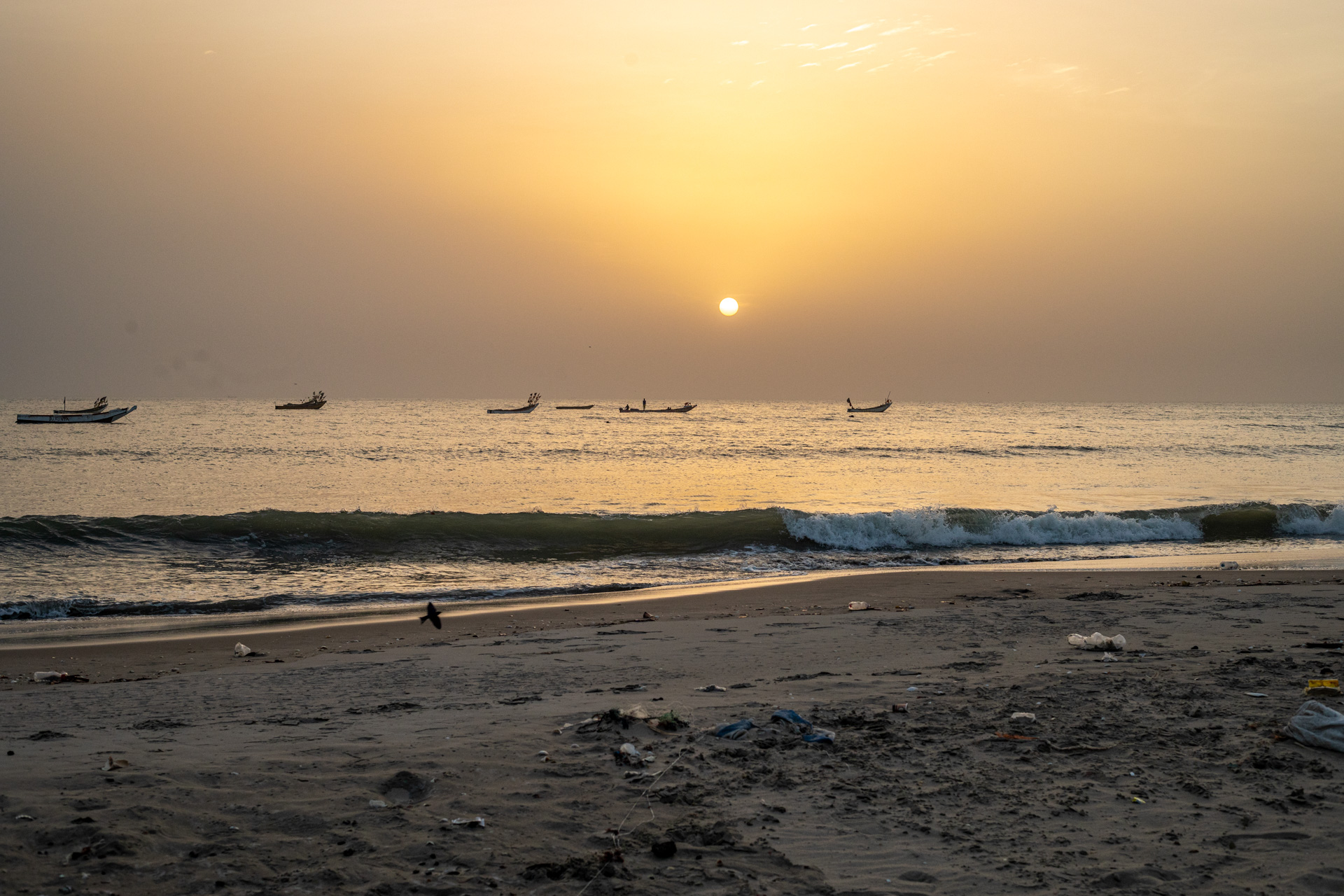The sun sets over the wooden fishing pirogues as the sea washes the quiet beach at the Kartong, The Gambia fishing grounds. Photo credit: Abubacar Fofana