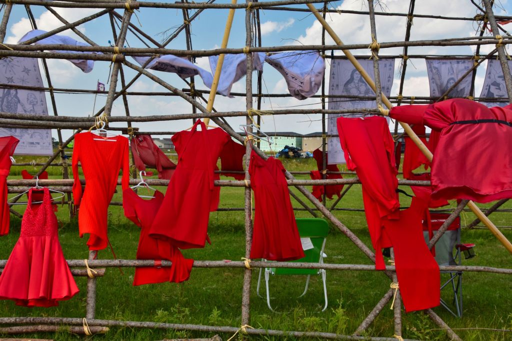 Numerosos vestidos rojos cuelgan de la ventana de una casa y se mueven por la brisa de un soleado día de verano.