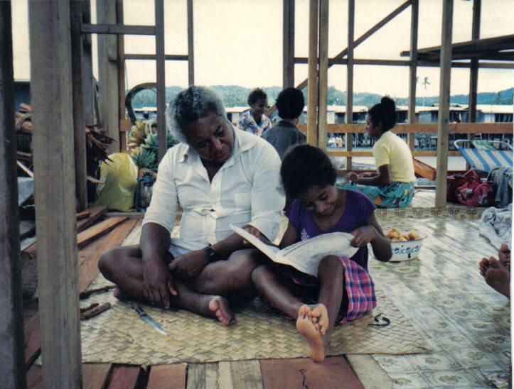 Patekalani Ila’ava, among the first native public servants in Papua New Guinea, sits beside his granddaughter Patricia, who is teaching her how to read in their home in Viriolo village, in 1988.