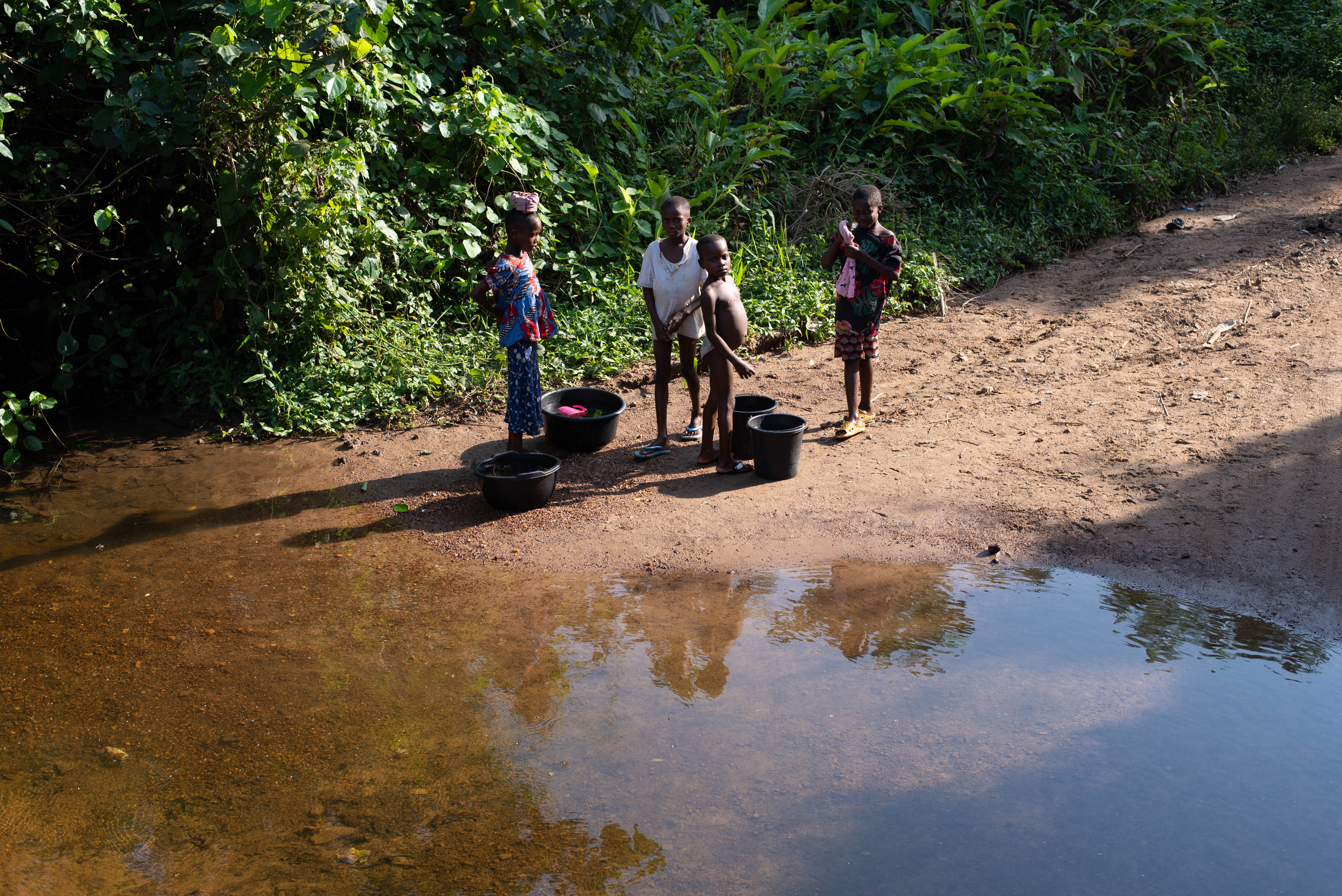 Children in Langbin gather at the river to collect water for their families. As the community’s only source for drinking and daily use, the river is also tied to a recurring health crisis, with many residents, particularly children, experiencing symptoms such as blood in their urine. Photo credit: Bukunmi Oyewole, December 11, 2020.