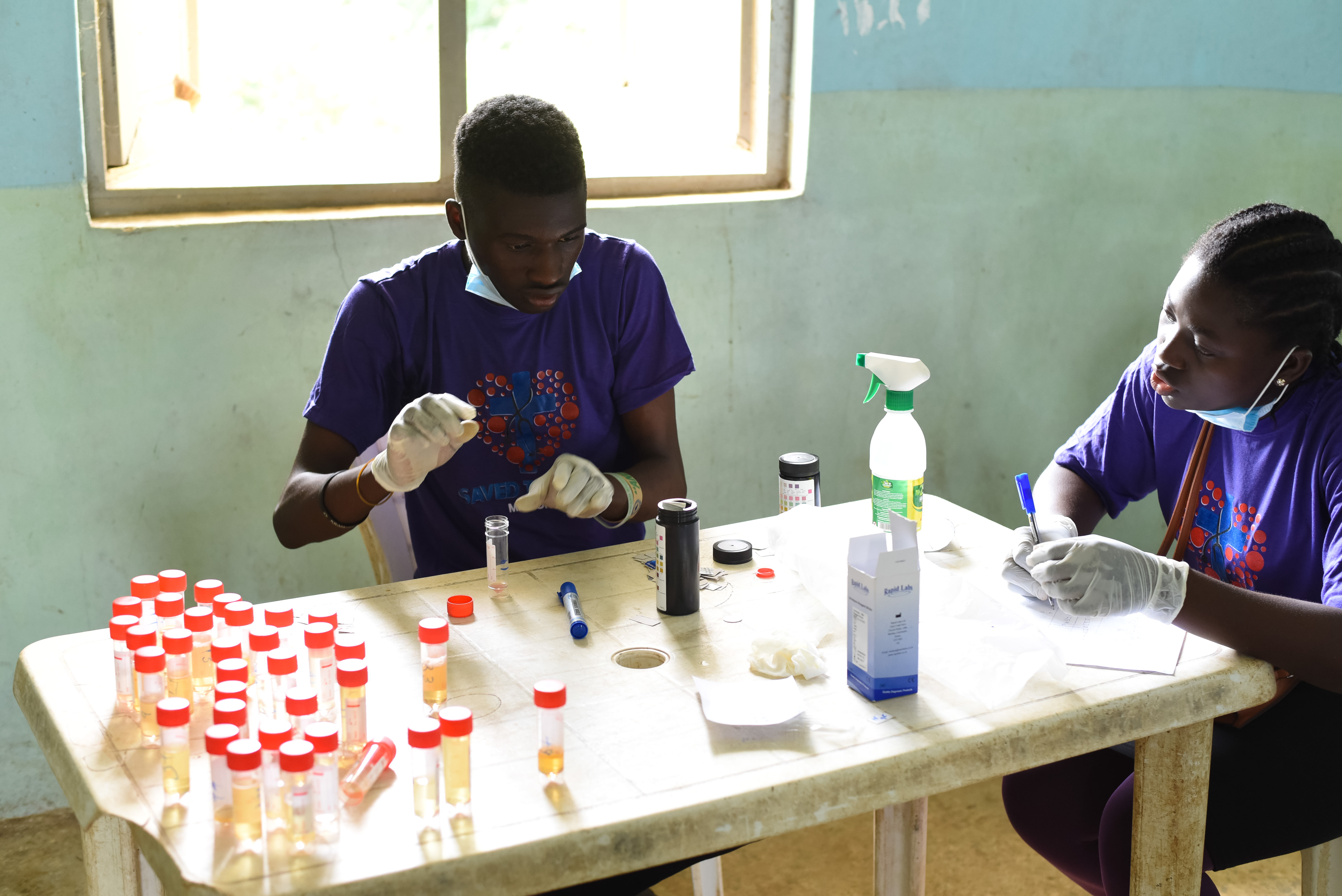 Inside a makeshift laboratory in Langbin, medical laboratory scientists process dozens of samples collected during the outreach. This rapid on-site testing is critical for diagnosing water-borne infections immediately, allowing the team to provide over 250 residents with the necessary medications before the day’s end. Photo credit: Bukunmi Oyewole, December 11, 2020.