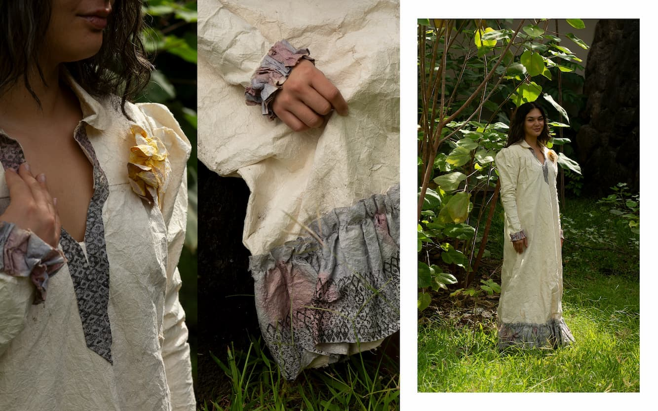 Three images display different perspectives of a woman with long brown hair wearing a vintage-style floor-length dress made of white bark cloth. The far-left image shows a close-up of the neckline and boutonniere detailing on the dress. The neckline is collared and dips into a conservative V-shape. The hem is dyed blue and stamped in black ink with a pattern of diamond shapes with circles at their centers. The woman holds her hand up to her collarbone, showcasing the dyed blue and pink ruffled edge of the long sleeve. The boutonniere is made of bark cloth, shaped like a flower petal, and dyed goldenrod. The middle image shows a close-up of the bottom hem of the dress, revealing a wide ruffle dyed in blue and pink and stamped with the same diamond pattern along the edgeline. The woman's hand is holding the dress, showcasing the sleeve ruffle detail. The final image showcases a wide shot of the woman and the dress from head to toe. She stands backdropped by tall mulberry trees within a patch of sunlight.